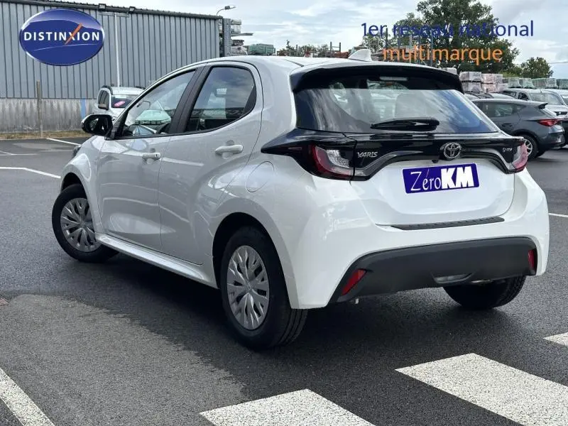 Toyota Yaris 116h Dynamic blanc lunaire vue 3/4 arrière droit, avec feux arrière noirs et hayon distinctif.