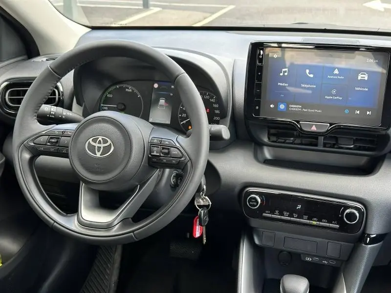 Vue intérieure centrée sur le volant et le tableau de bord de la Toyota Yaris 116h Dynamic 2025 avec écran tactile allumé.