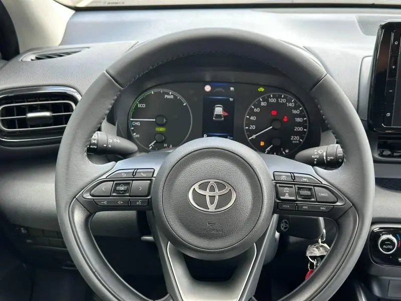 Vue centrée du volant noir de la Toyota Yaris 116h Dynamic 2025 avec tableau de bord hybride et commandes intégrées.