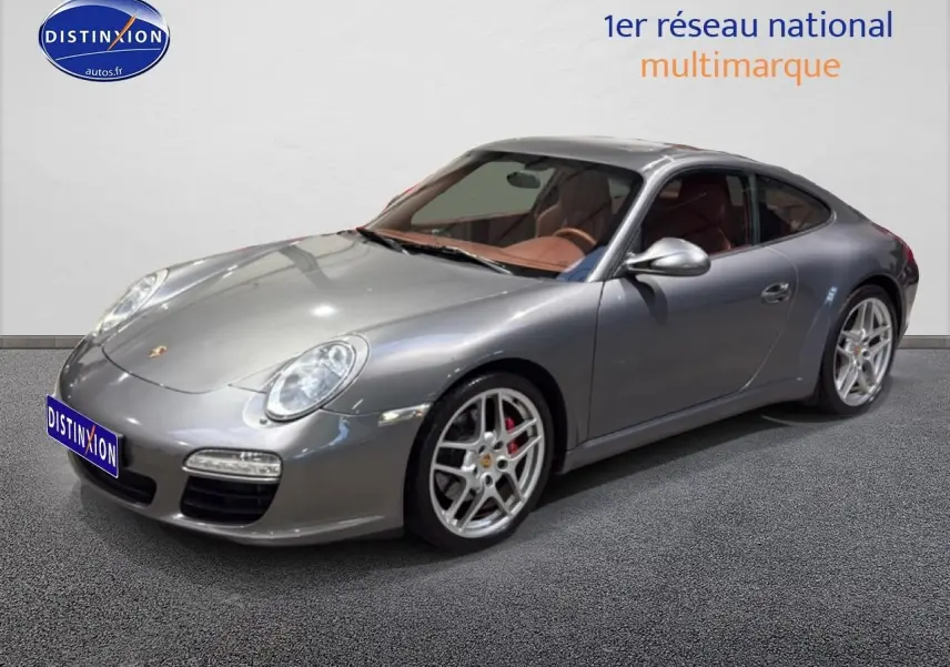 Porsche 911 (997) carrera pdk gris en 3/4 avant droit avec jantes alu et intérieur cuir marron visible.