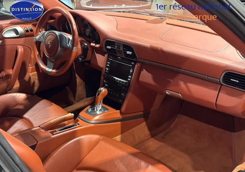 Vue intérieure côté conducteur de la Porsche 911 (997) carrera pdk 2009 avec cuir brun et console centrale automatique.