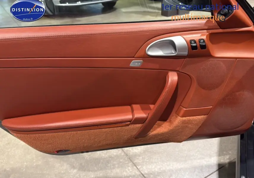 Détail de la porte côté conducteur en cuir marron rouge de la Porsche 911 (997) Carrera PDK gris, avec commande vitres et poignée alu.