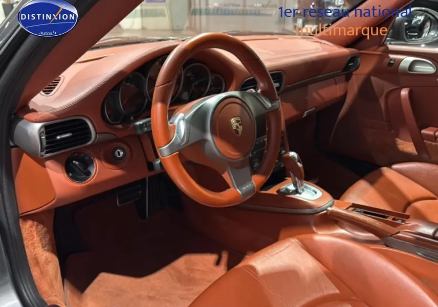 Vue intérieure côté conducteur de la Porsche 911 (997) carrera pdk 2009 avec cuir marron et volant sport.