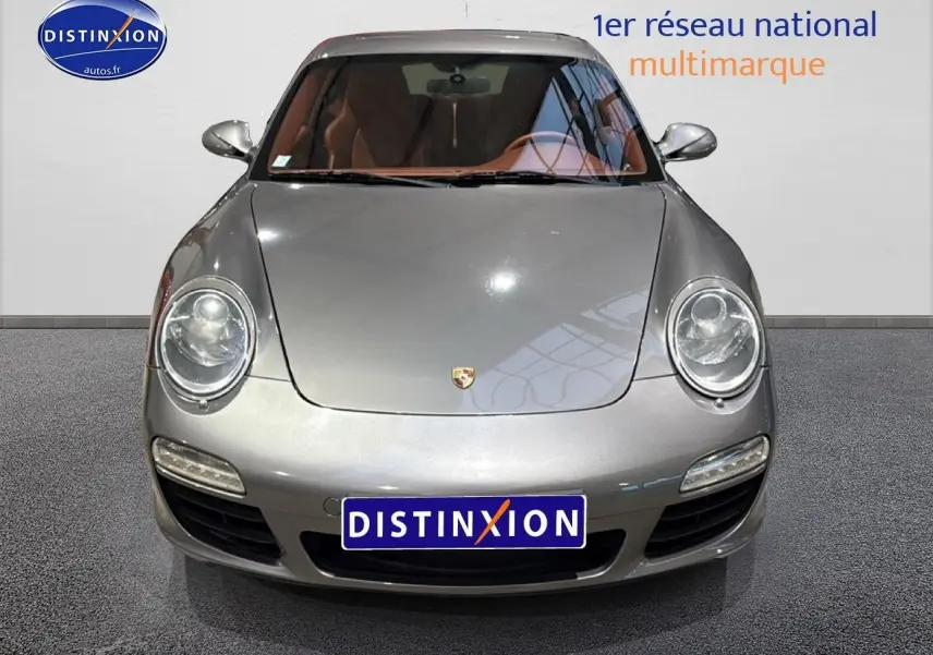 Vue frontale d'une Porsche 911 (997) carrera pdk gris métallisé avec phares bi-xénon et intérieur cuir marron visible.
