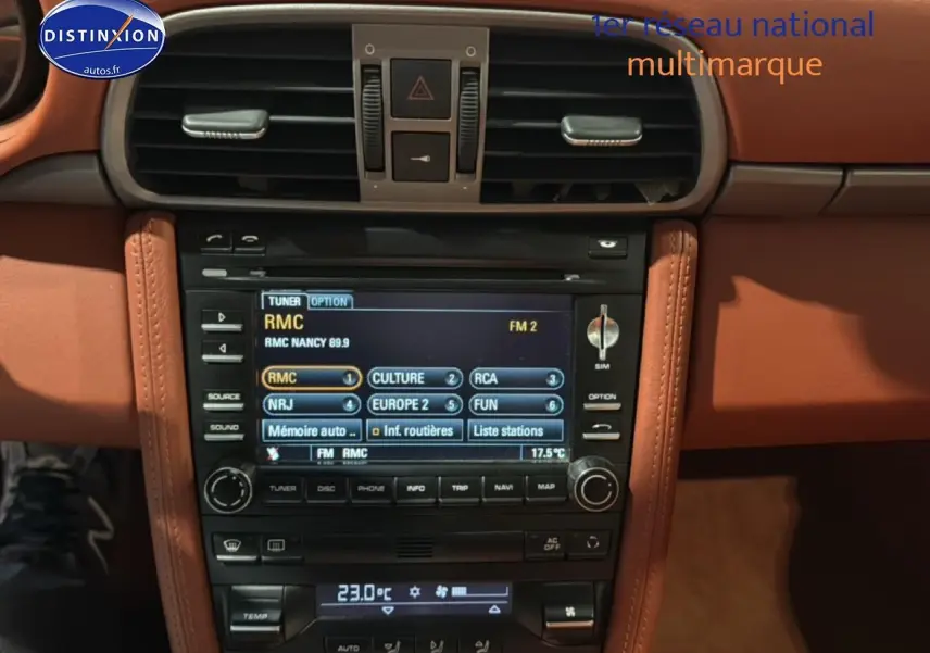 Vue rapprochée de la console centrale en cuir marron du Porsche 911 (997) carrera pdk avec écran multimédia et commandes clim.