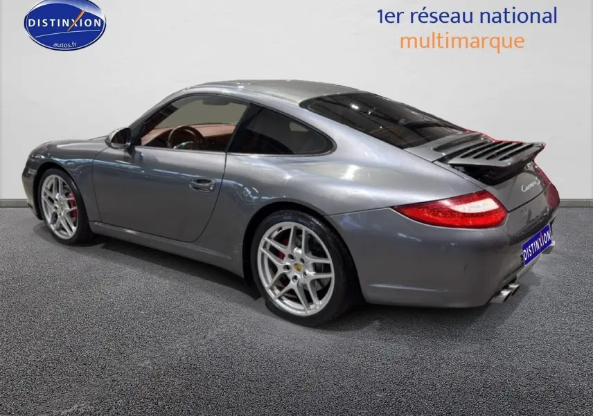 Vue 3/4 arrière droite d'une Porsche 911 (997) Carrera PDK gris métallisé avec jantes alu et aileron déployé.