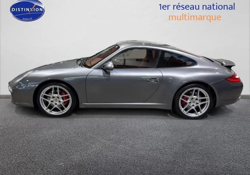 Profil côté gauche d'une Porsche 911 (997) Carrera PDK gris métallisé avec jantes alu et aileron arrière déployé.