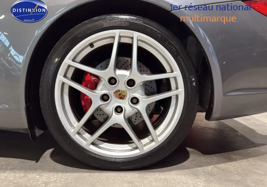 Gros plan sur la jante alu argentée et le frein rouge d'une Porsche 911 (997) carrera gris côté arrière droit.