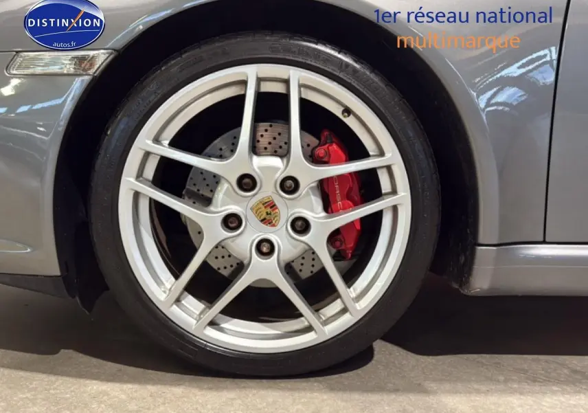 Gros plan sur la jante alu argentée et l’étrier de frein rouge du côté avant droit d’une Porsche 911 gris métallisé.