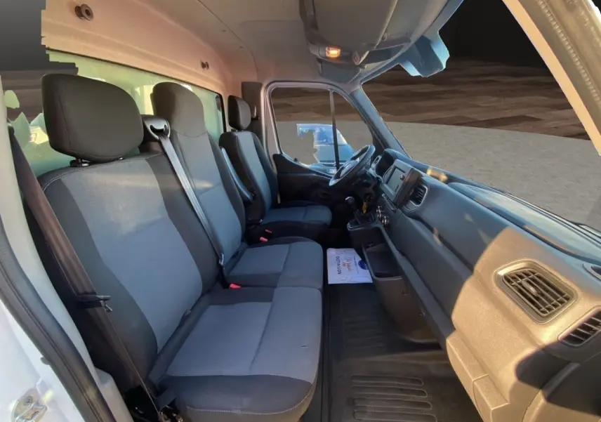 Vue intérieure côté conducteur du Renault Master blanc, montrant les sièges avant et le tableau de bord fonctionnel.