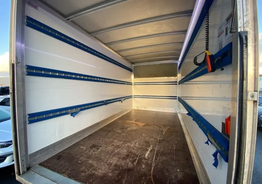 Vue intérieure de la caisse blanche du Renault Master 2023, montrant l'espace de chargement avec rails bleus sur les parois.