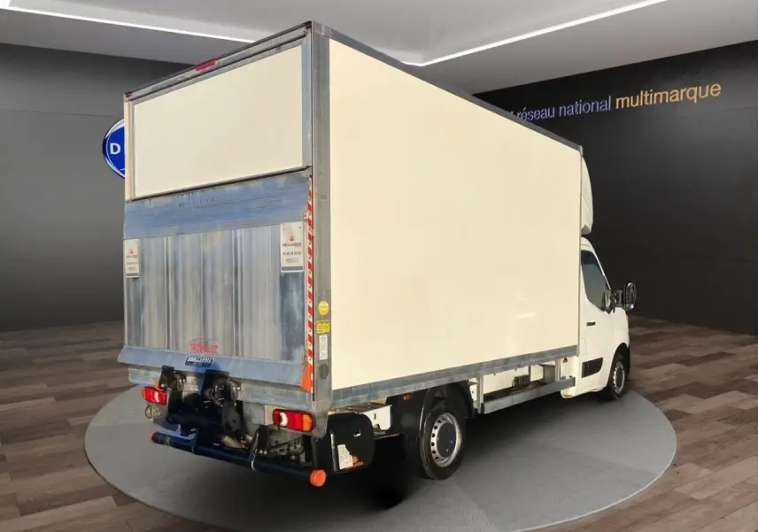 Vue 3/4 arrière droite d’un utilitaire Renault Master blanc avec caisse fermée et hayon élévateur métallique.