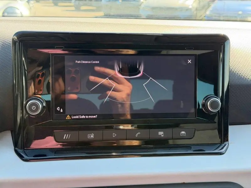 Écran tactile central en gros plan dans l'habitacle du SEAT Arona gris, affichant l'aide au stationnement.