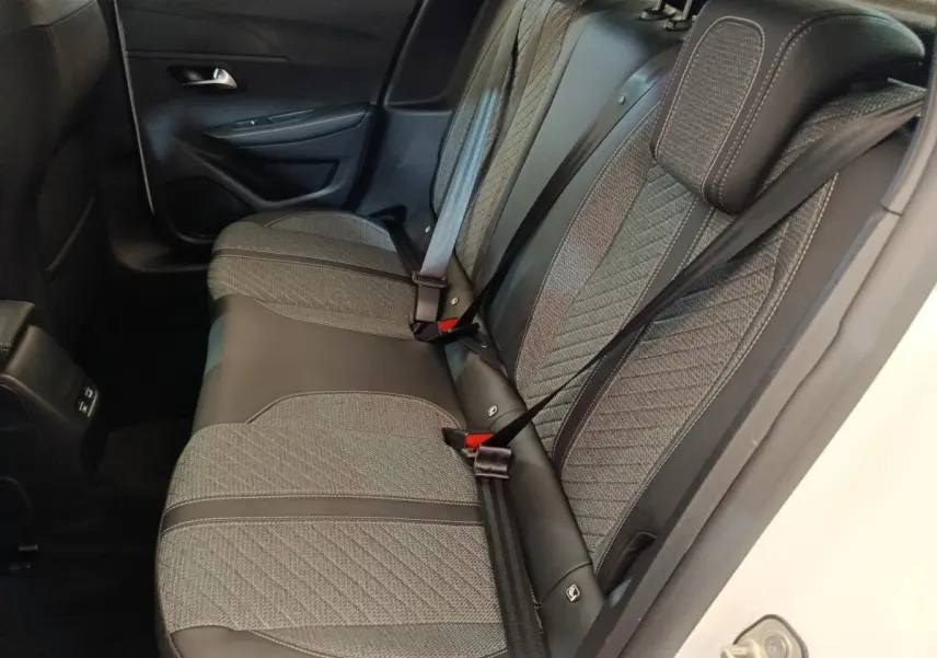 Vue intérieure côté droit sur la banquette arrière grise et noire du Peugeot 208 électrique blanc 2024.