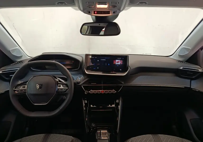 Vue intérieure frontale du tableau de bord et volant cuir noir de la Peugeot 208 électrique 2024, avec écran tactile central.