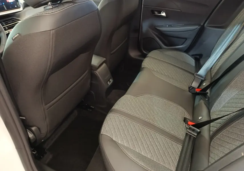 Vue intérieure arrière droite de la banquette tissu et cuir gris foncé de la Peugeot 208 électrique blanche 2024.