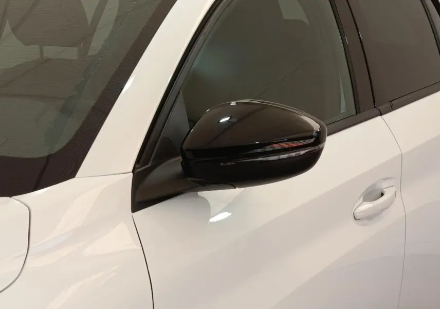 Gros plan sur le rétroviseur noir et la portière blanche côté gauche d'une Peugeot 208 électrique 2024.