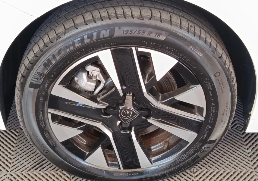 Gros plan sur la roue avant droite blanche d’une Peugeot 208 électrique 2024 avec jante noire et argentée design.