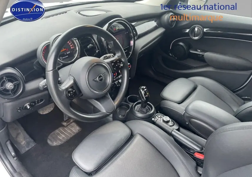 Vue intérieure côté conducteur d'une MINI 1.5 136CH 2023 avec sellerie cuir noir et console centrale moderne.