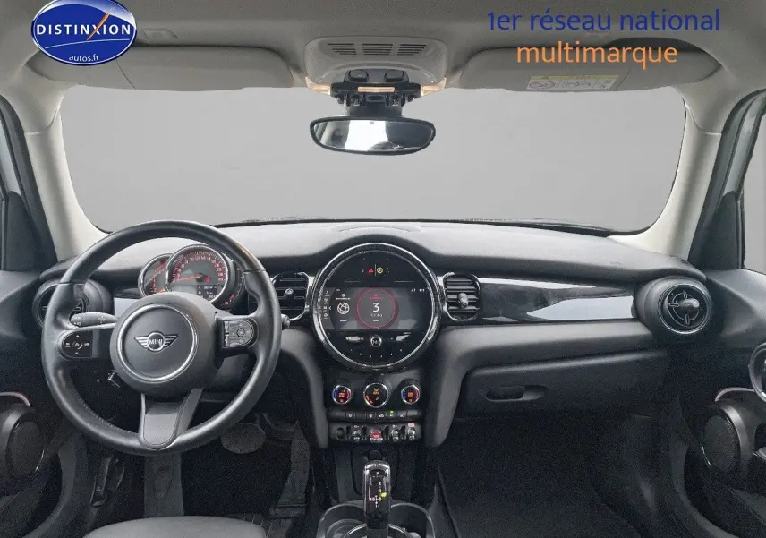 Tableau de bord et volant de MINI 1.5 136CH blanc nacré, vue frontale intérieure mettant en valeur l'écran central rond.