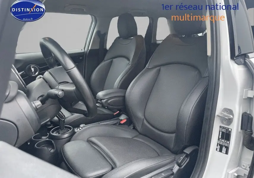 Intérieur de la MINI 1.5 136CH blanc nacré, vue côté conducteur montrant sièges en cuir noir et volant.