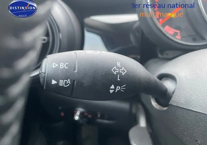 Gros plan sur la commande de clignotants à gauche du volant d'une MINI blanche nacrée 2023, avec marquages blancs visibles.