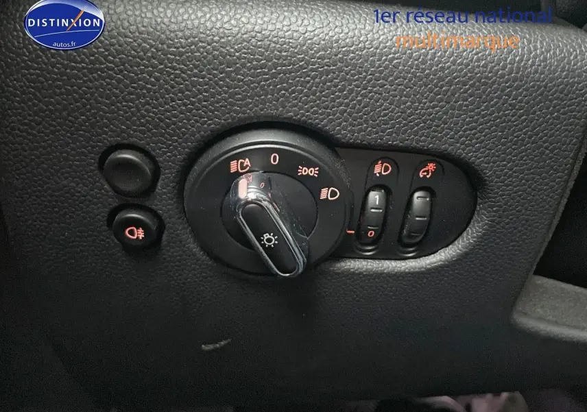 Gros plan sur les commandes d'éclairage intérieures d'une MINI blanche nacrée 2023, avec boutons rétroéclairés rouges.