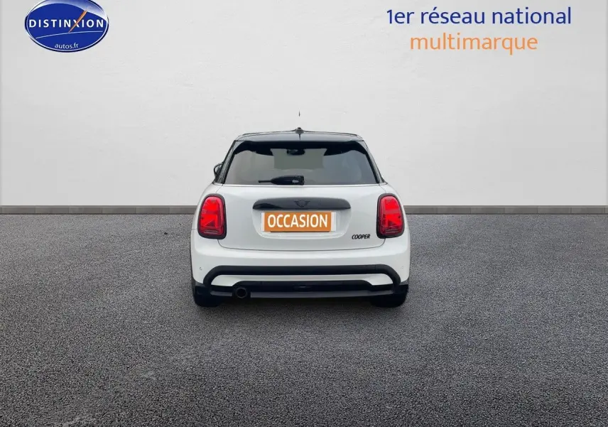 Vue arrière d'une MINI Cooper blanche nacrée 2023 avec toit noir et feux arrière rouges distinctifs.