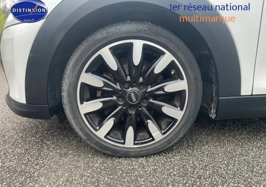 Gros plan sur la roue avant droite d'une MINI blanche nacrée avec jante noire et argentée au design distinctif.