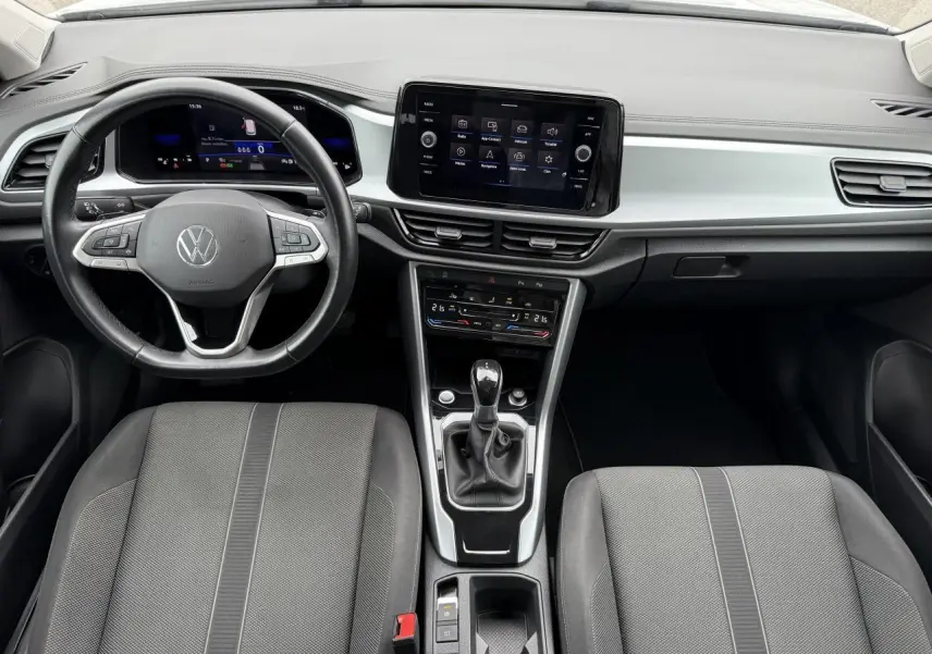 Vue intérieure frontale du tableau de bord et volant du Volkswagen T-Roc 2022 avec écran tactile central et sièges gris.