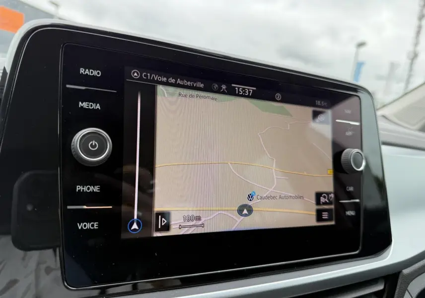 Écran tactile du système de navigation du Volkswagen T-Roc blanc, vue intérieure centrée sur la carte GPS.