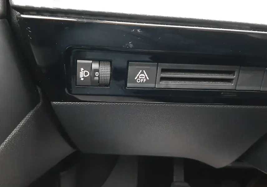 Détail intérieur du tableau de bord côté conducteur de la Peugeot 508 blanc, avec commandes d'éclairage et d'aide à la conduite.
