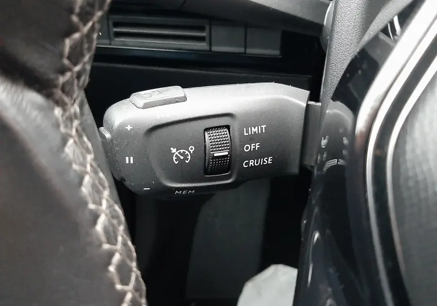 Gros plan sur la commande de régulateur de vitesse à gauche du volant d’un Peugeot 508 blanc de 2018.
