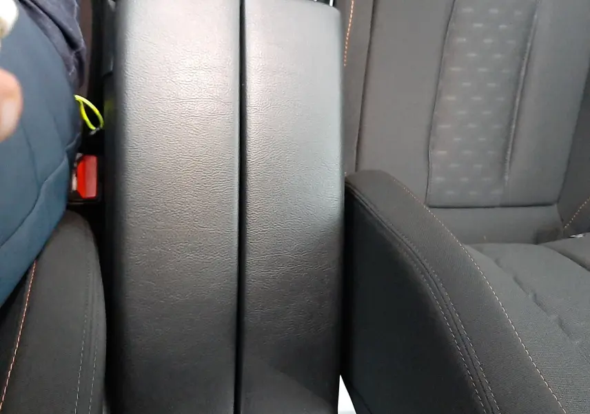 Vue rapprochée de l'accoudoir central noir entre les sièges avant gris foncé du Peugeot 508 blanc de 2018.