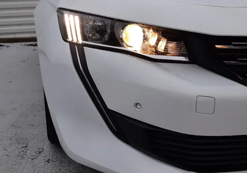 Gros plan sur l'avant droit blanc d'une Peugeot 508 1.5 BlueHDi 130 avec phares allumés et feux LED distinctifs.