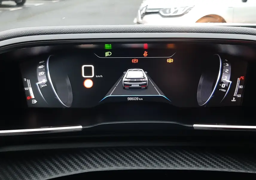 Vue du tableau de bord numérique de la Peugeot 508 blanche, affichant la vitesse à 0 km/h et le kilométrage.