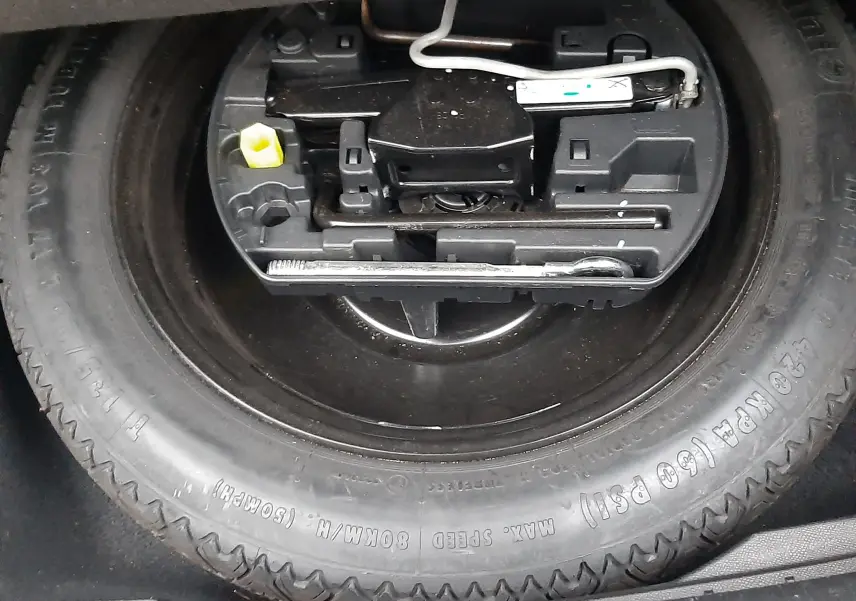 Gros plan sur la roue de secours et le kit d'outils dans le coffre d'une Peugeot 508 blanche 1.5 BlueHDi 130 de 2018.