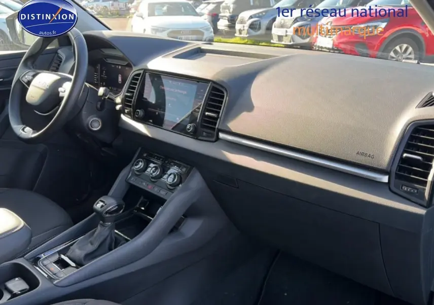 Vue intérieure côté passager du tableau de bord et console centrale du Skoda Karoq gris 2025 avec écran tactile et volant multifonction.