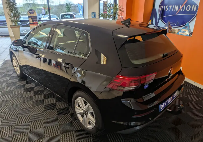 Volkswagen Golf 1.5 eTSI Style noire vue 3/4 arrière droit en intérieur avec toit et jantes visibles.