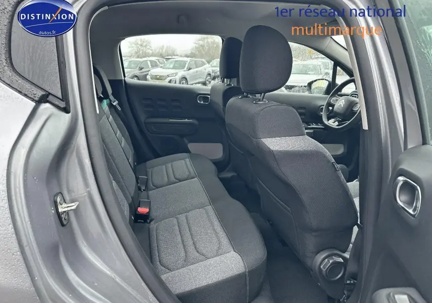 Vue intérieure côté gauche montrant les sièges arrière et avant en tissu gris d'une Citroën C3 gris acier 2023.