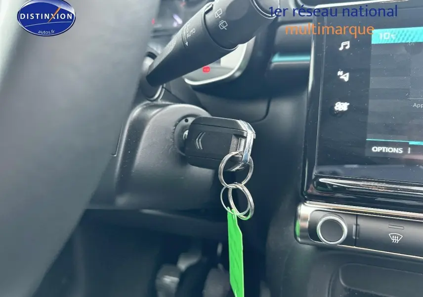 Gros plan intérieur sur le contacteur de clé et l’écran tactile d’une Citroën C3 gris acier, version 2023.