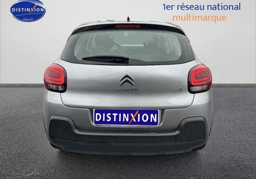 Vue arrière d'une Citroën C3 gris acier 2023 avec feux arrière allumés et pare-chocs noir.