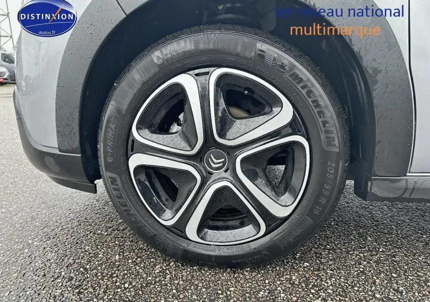 Gros plan sur la roue avant gauche avec jante alliage noire et argentée d'une Citroën C3 gris acier.