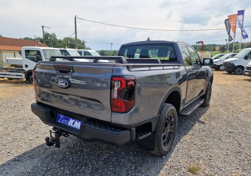 Ford Ranger Super Cabine gris carbone, vue 3/4 arrière droit, avec barres de plateau et marchepieds noirs.