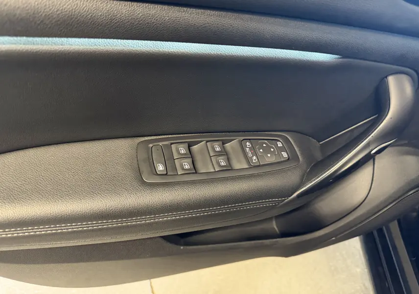 Gros plan sur la commande des vitres et rétroviseurs côté conducteur de la Renault Mégane Estate noire 2024.