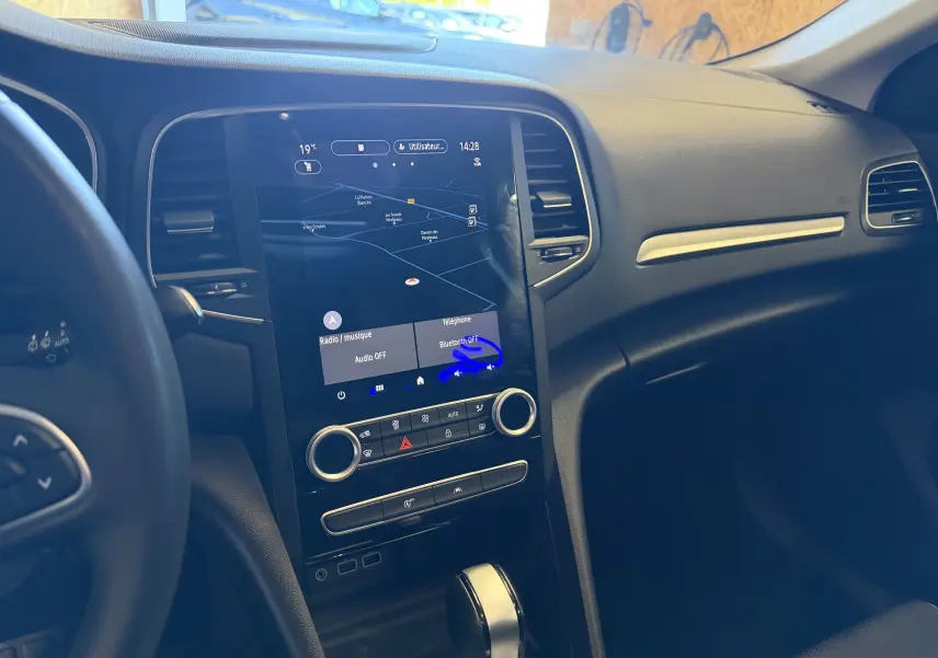 Vue intérieure centrée sur la console centrale tactile et le levier de vitesse de la Renault Mégane Estate 2024 noire.