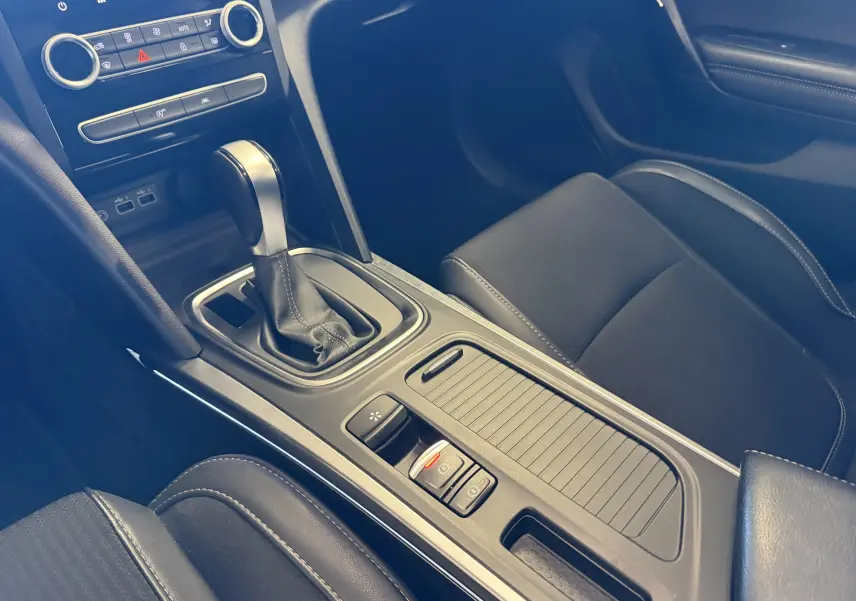 Vue rapprochée de la console centrale intérieure noire de la Renault Mégane Estate 2024 avec boîte auto et frein de parking électrique.