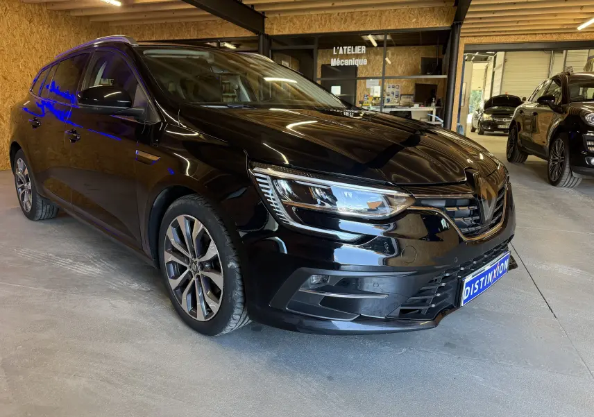 Renault Mégane Estate noir étoilé vue 3/4 avant droit dans un atelier, avec phares LED et jantes alliage.