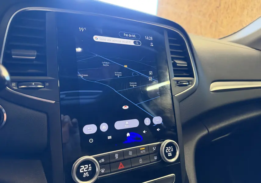 Vue rapprochée de l’écran tactile central et de la console de la Renault Mégane Estate 2024, affichant la navigation et la climatisation.