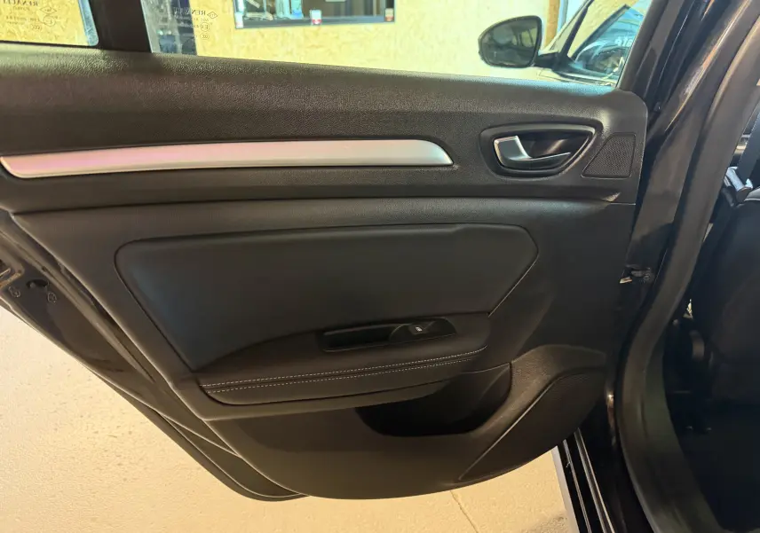 Vue intérieure du panneau de porte arrière droite noir mat avec poignée argentée et commande de vitre sur Renault Mégane Estate 2024.